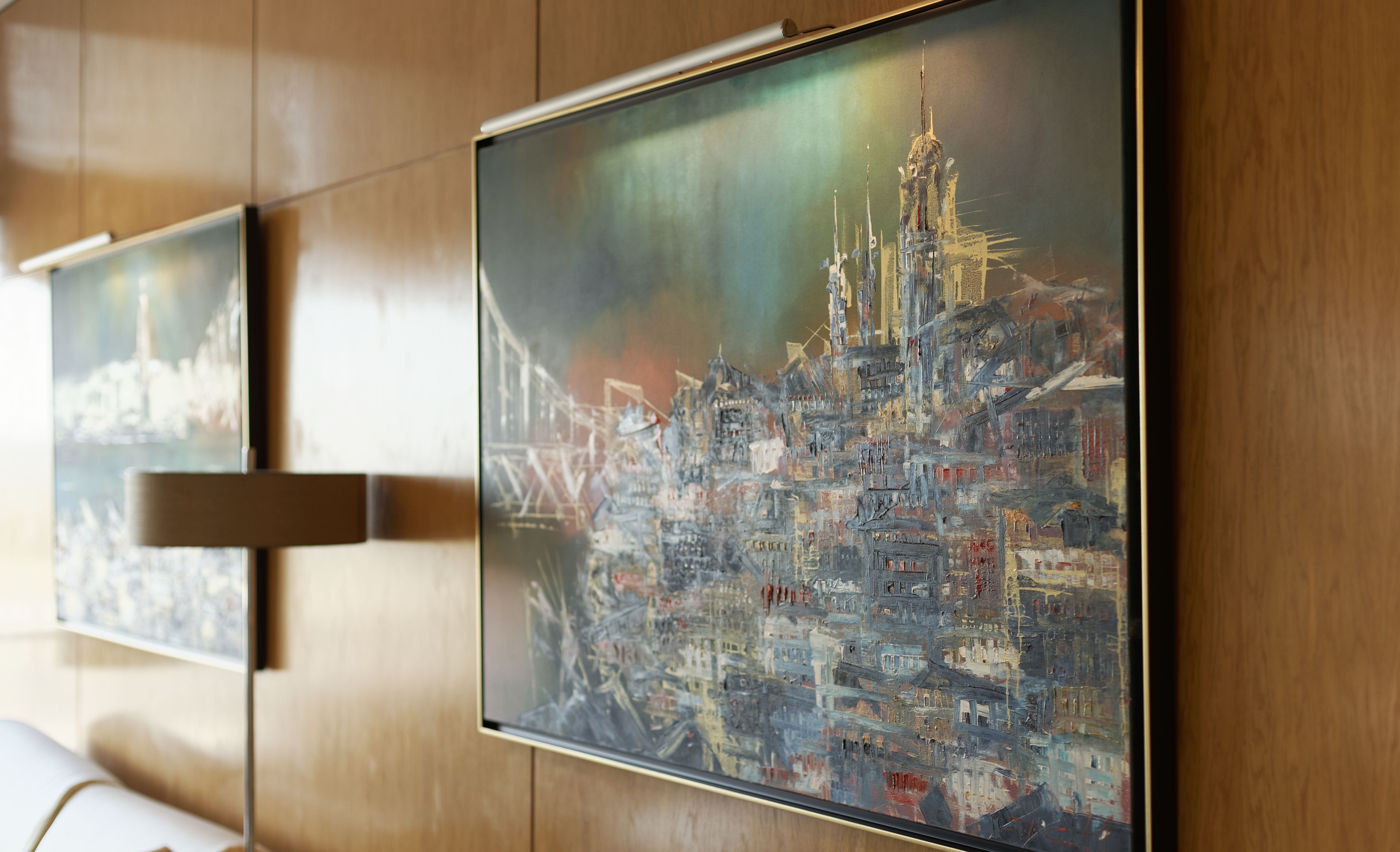 Een muur met drie ingelijste kunstwerken die stadsgezichten voorstellen.