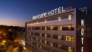 A modern hotel building with the name "Mercure HOTEL" prominently displayed. It features multiple floors with large windows and a flat facade. - Mercure Lisboa Almada (Almada)