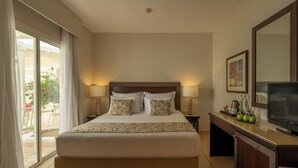 Une chambre d’hôtel avec un grand lit, deux lampes de chevet, une télévision et un bureau équipé d’une machine à café et agrémenté d’objets décoratifs.