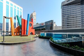 Una plaza urbana moderna con una escultura grande y colorida, una piscina y edificios contemporáneos.