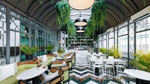 Un interior moderno con zonas de estar, un bar y plantas colgantes.