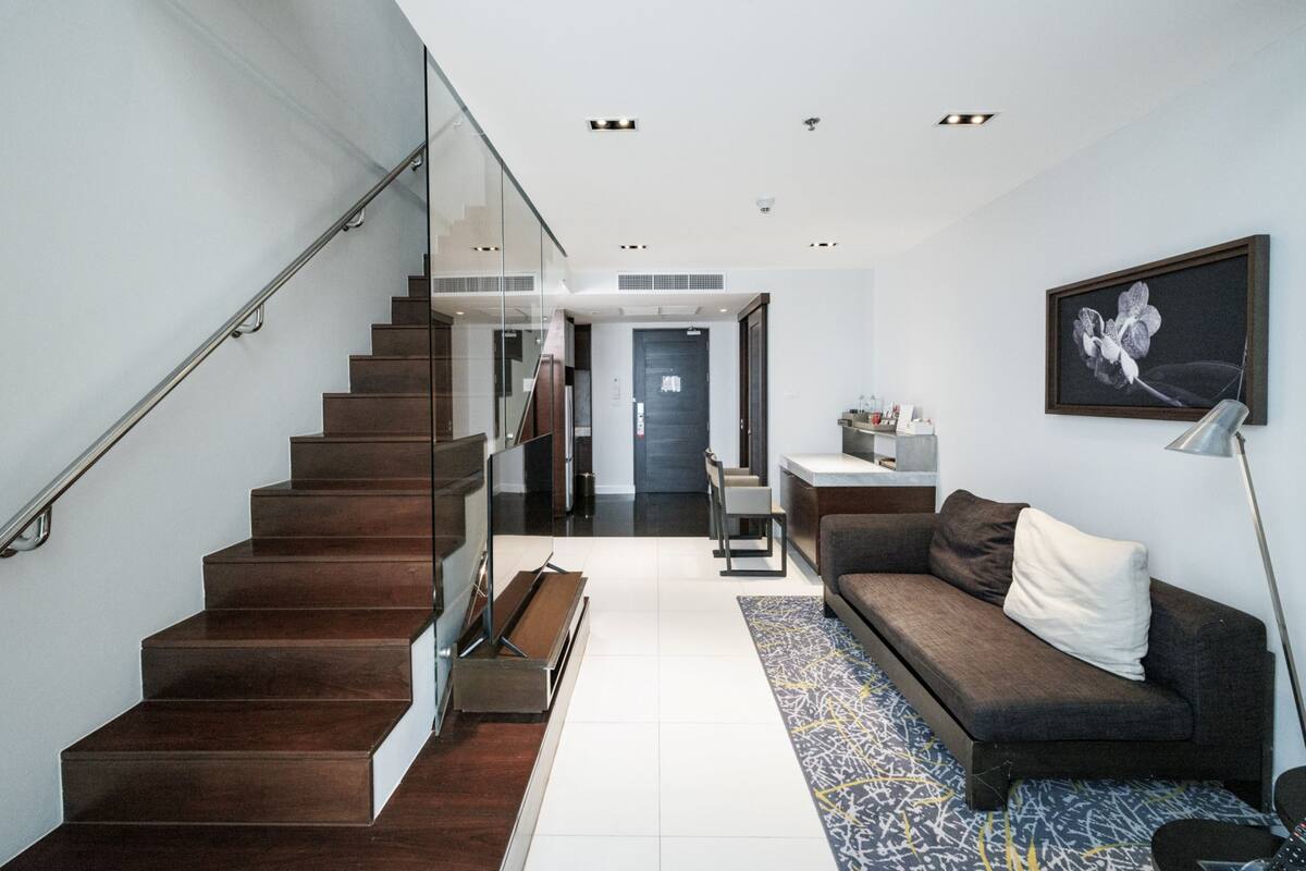 A modern living room with a staircase, a sofa, a coffee table, and a framed picture on the wall.