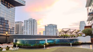 Un área de piscina en la azotea con un horizonte urbano al fondo, rodeada de vegetación y arquitectura moderna.