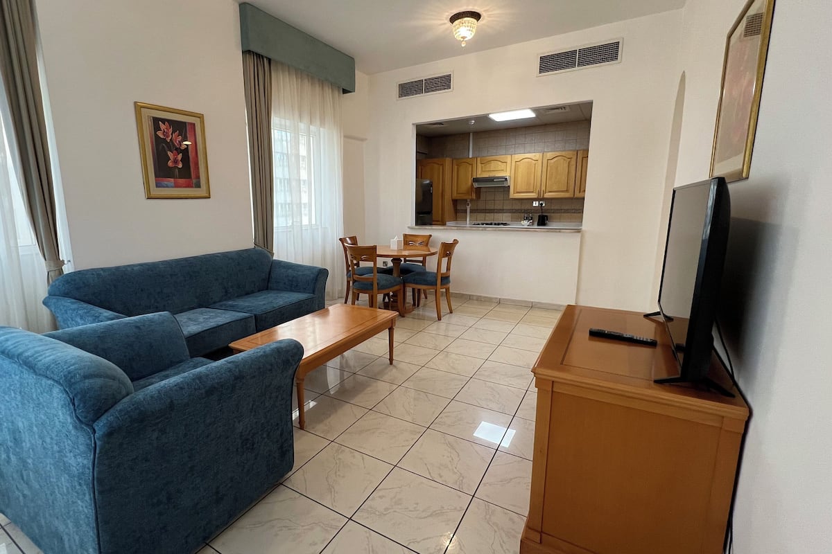 A living room with a blue sofa, a wooden coffee table, and a TV on a wooden stand.