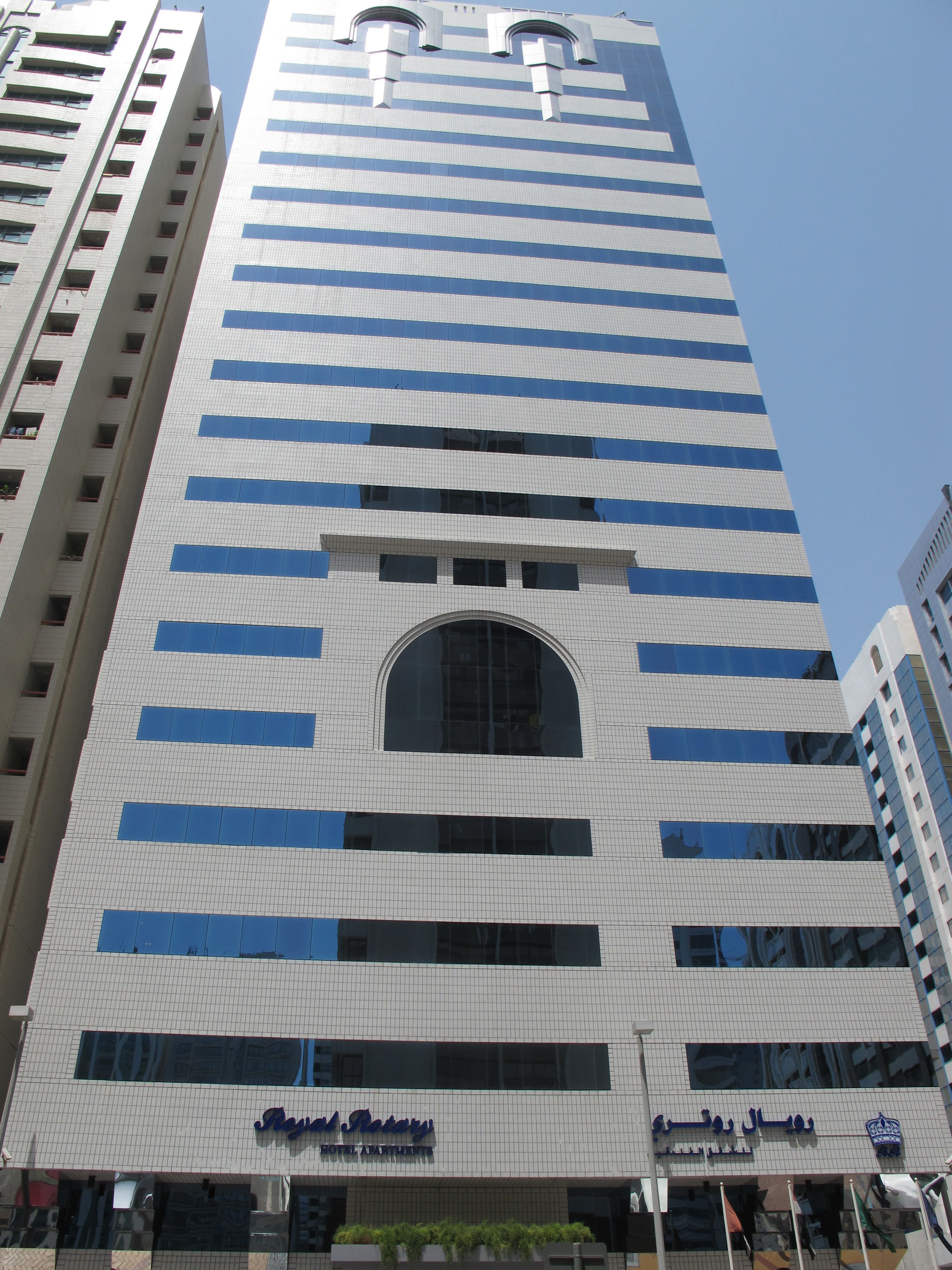 Un hotel con diseño moderno, que destaca por una entrada abovedada y numerosas ventanas.