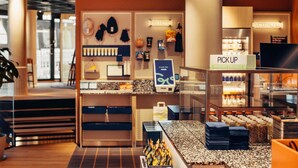 A hotel reception area with a counter, a sign that says 'PICK UP,' and a display of bottled water. - Scandic Go, Grensen 20 (Oslo)