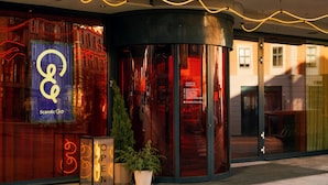 A hotel entrance with a glass door, a neon sign, and a potted plant. - Scandic Go, Grensen 20 (Oslo)