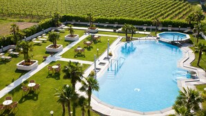 A large swimming pool surrounded by palm trees, lounge chairs, and a well-maintained lawn. - Hotel Savoy Palace - Tonelli Hotels (Riva del Garda)