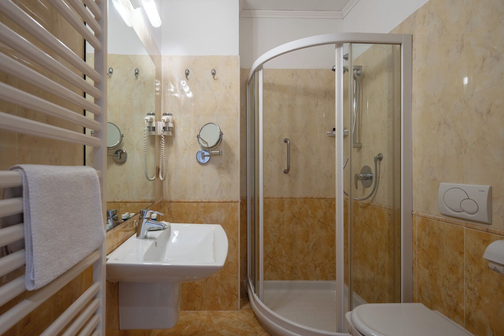 A modern bathroom with a glass-enclosed shower, a sink with a mirror, and a towel rack.