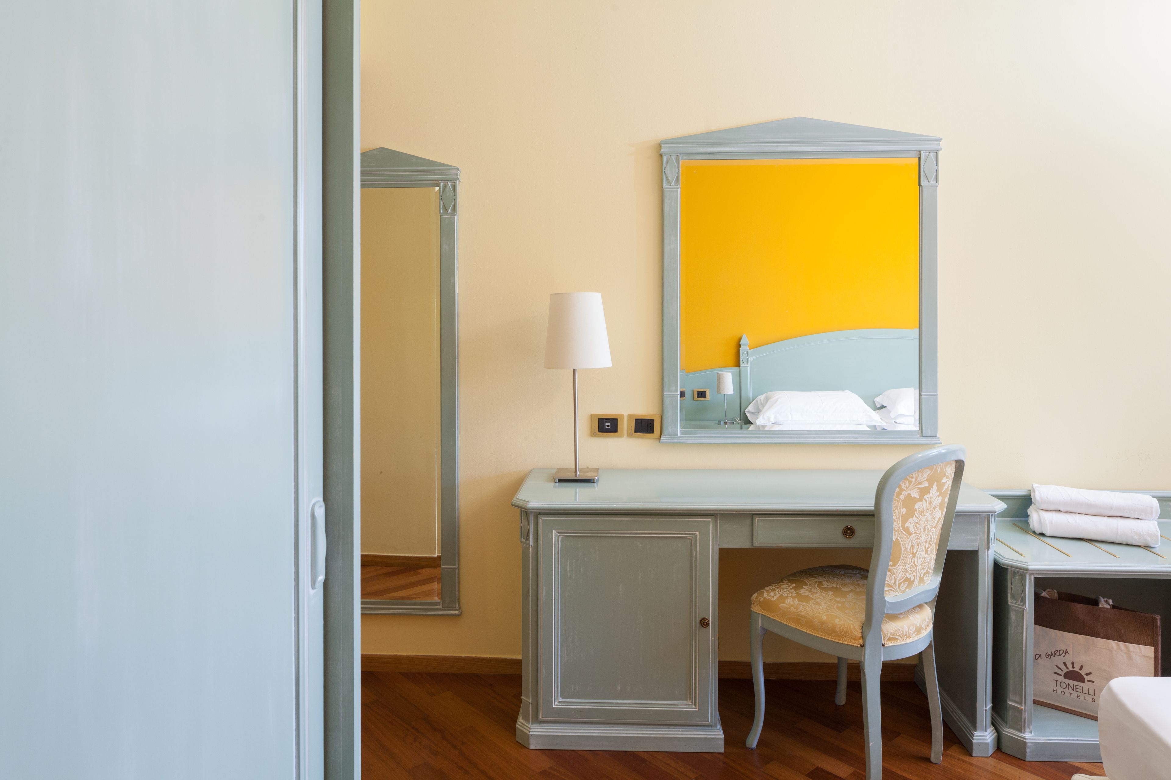 Een hotelkamer met een bureau, stoel en een grote spiegel.