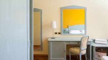 Een hotelkamer met een bureau, stoel en een grote spiegel.