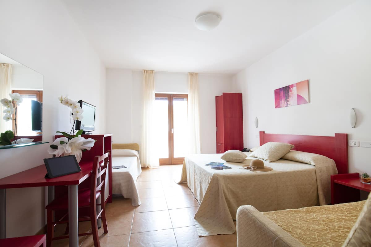 Une chambre d’hôtel avec un lit, un bureau avec un ordinateur, une chaise et un téléviseur.