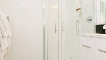 Un baño moderno con cabina de ducha de vidrio, un lavamanos blanco y un perchero para toallas.