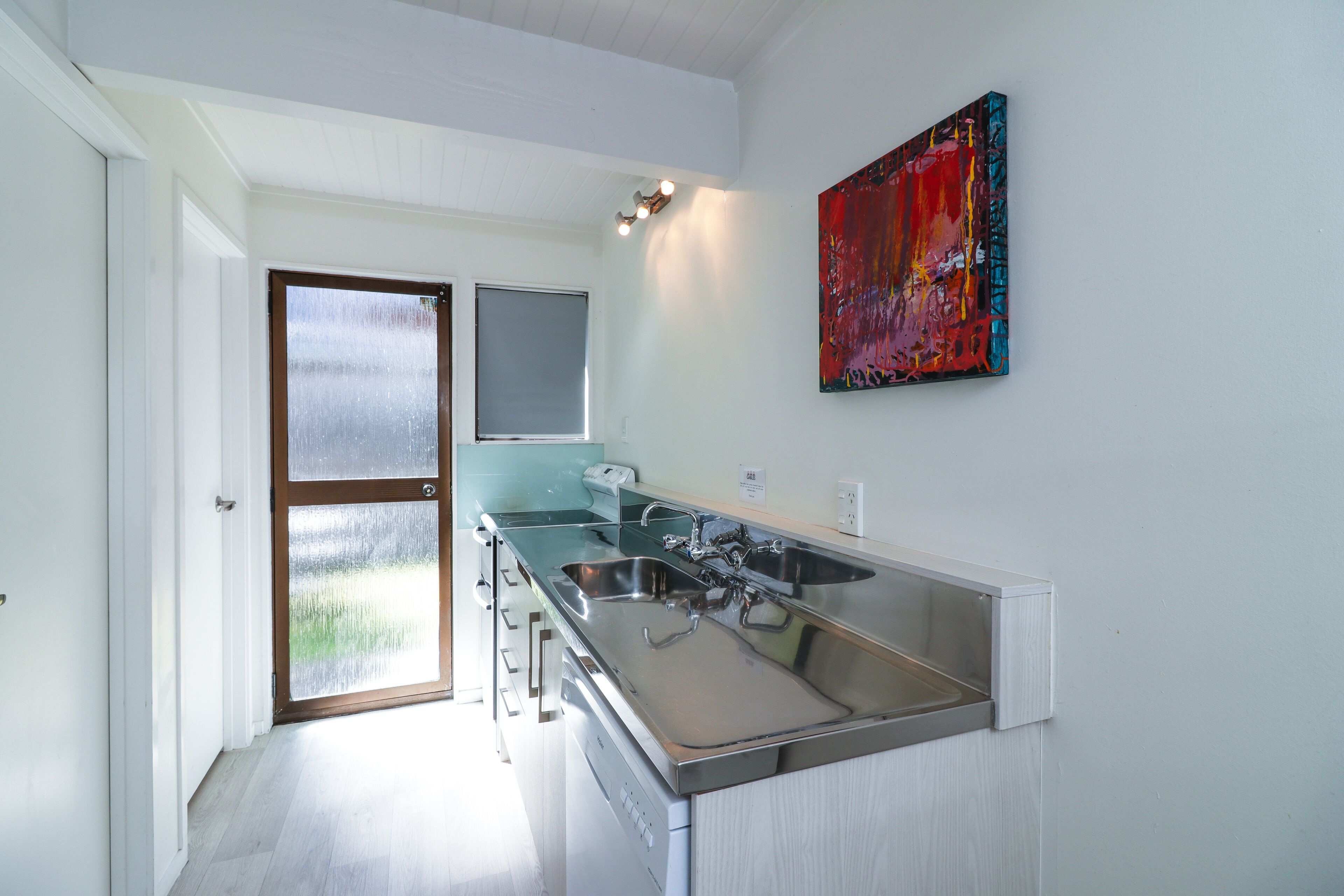 A modern kitchen with a large island, stainless steel appliances, and a colorful abstract painting on the wall.