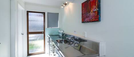 A modern kitchen with a large island, stainless steel appliances, and a colorful abstract painting on the wall.