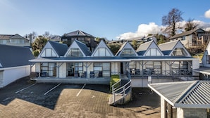 A modern building with a reception area, multiple windows, and a paved courtyard. - Gables Lakefront Motel (Taupo)