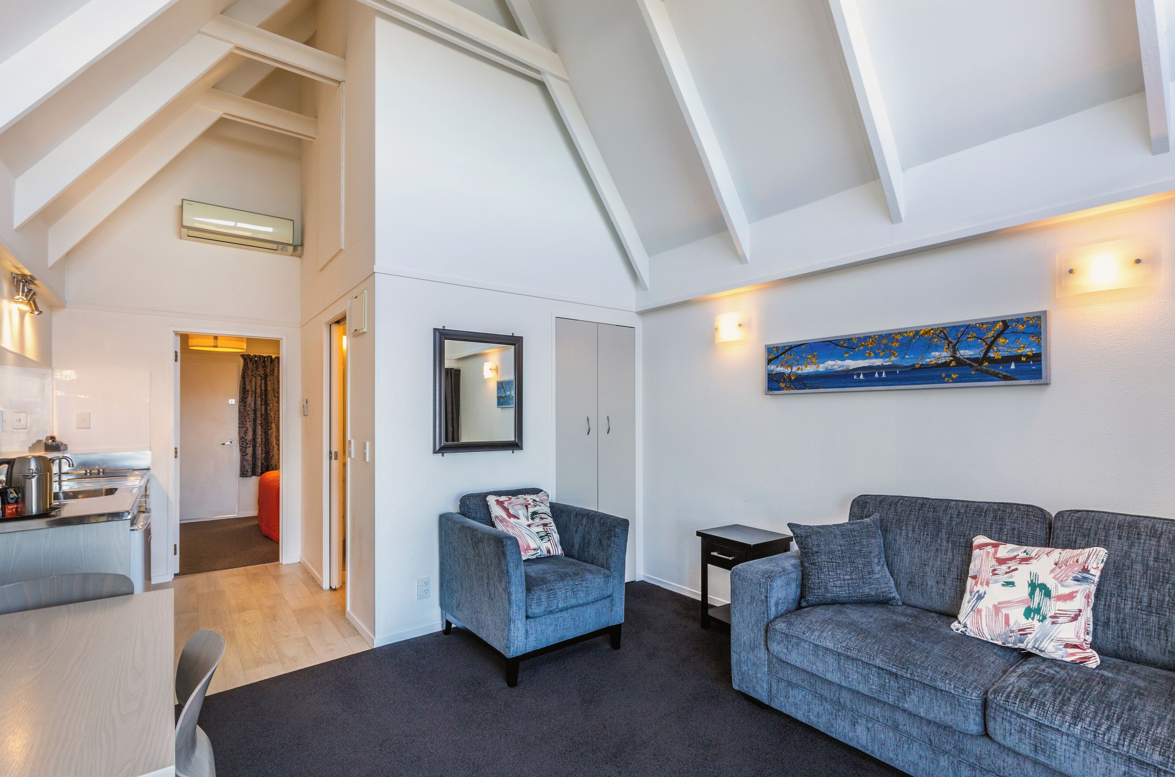 A modern living room with a grey sofa, a blue armchair, and a painting on the wall.