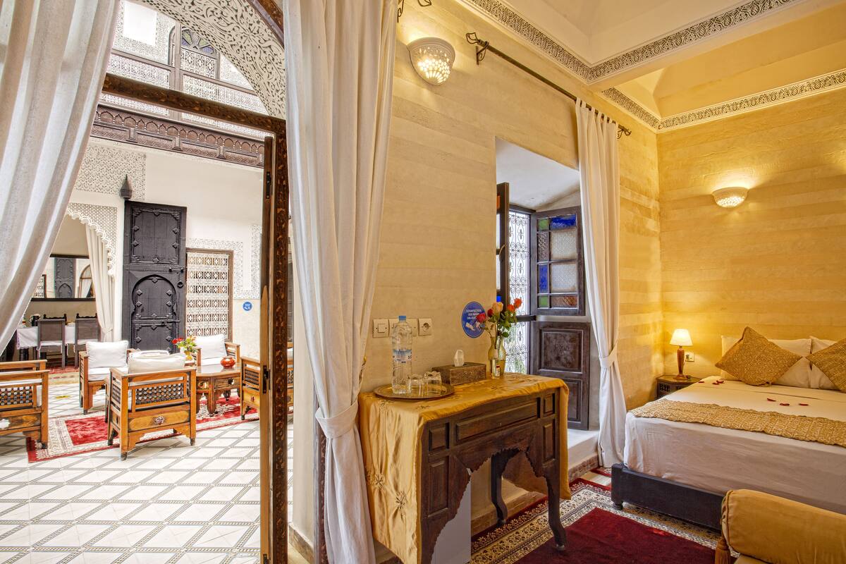 A traditional room with a bed, a wooden desk, and a mirror.