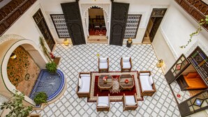 Un intérieur de style marocain avec un espace salon central, une petite piscine et des décorations murales en mosaïque.