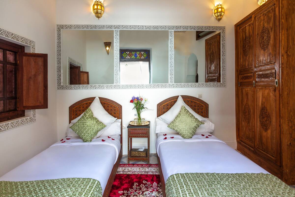 A room with two beds, a large mirror, and wooden wardrobes.
