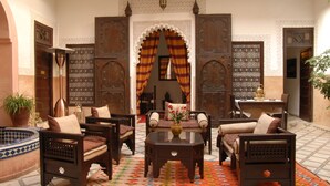 Un intérieur marocain traditionnel, avec des meubles en bois, un sol à motifs et des portes richement décorées.