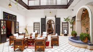 Un vaste espace de vie doté d’un haut plafond, d’un salon aménagé au centre et d’une fontaine décorative.