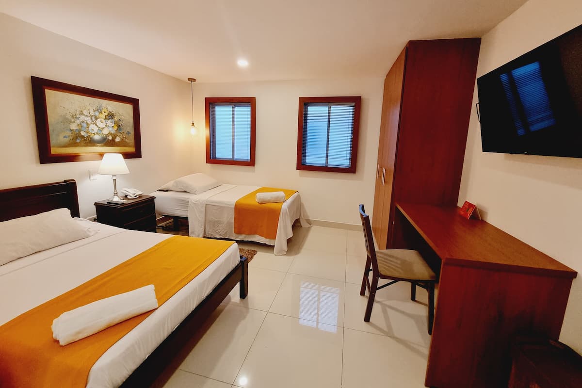 Habitación de hotel con dos camas, un escritorio, un televisor y un cuadro en la pared.