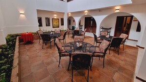 A spacious outdoor patio with multiple tables and chairs, surrounded by arches and a tiled floor. - Hotel Karlo (Cali)