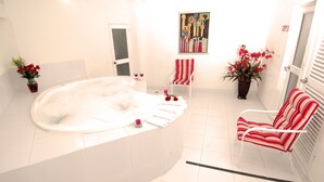 A bathroom with a large bathtub, a chair, and a painting on the wall. - Hotel Karlo (Cali)