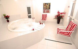 Un baño con una bañera grande, una silla y un cuadro en la pared.