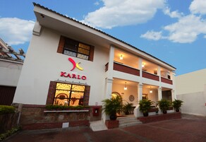 Un hotel llamado KARLO con fachada blanca, detalles rojos y un balcón.