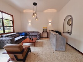 Una sala moderna con un sofá modular, una mesa de centro, un sillón pequeño, un mueble para televisión y un espejo decorativo.