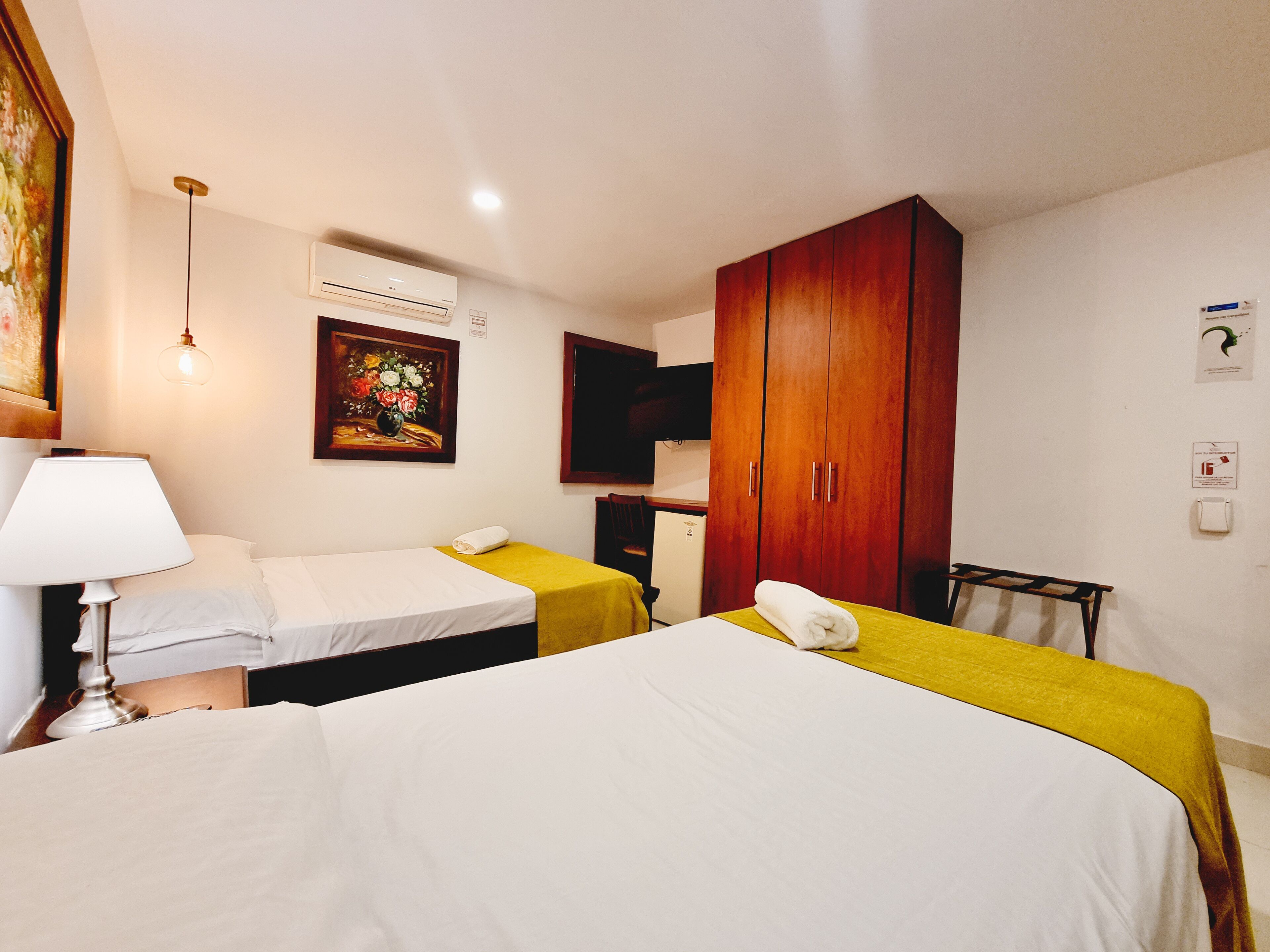 Ein Hotelzimmer mit zwei Betten, einem Schreibtisch, einem Sessel, einem Fernseher und einem Kleiderschrank.