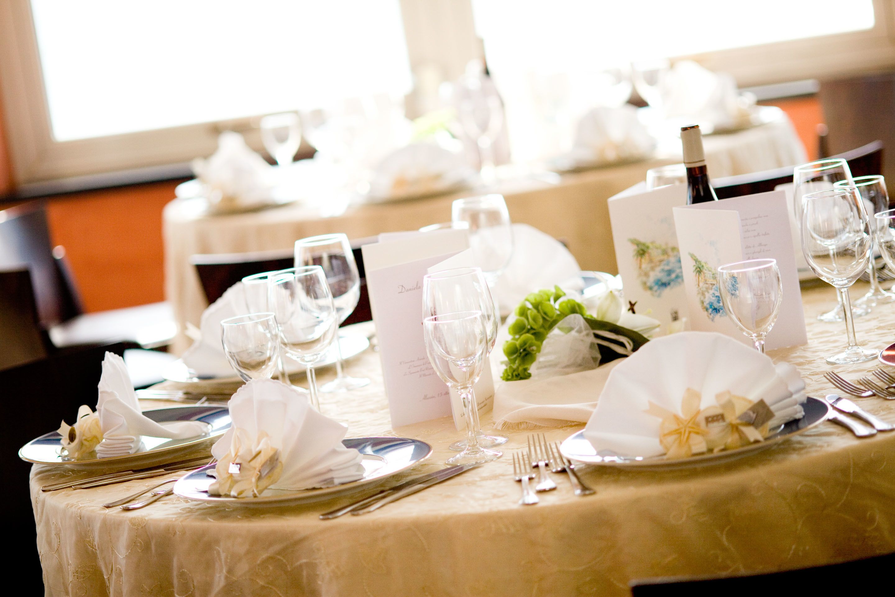 A table set for a formal event with white tablecloths, silverware, and wine glasses.