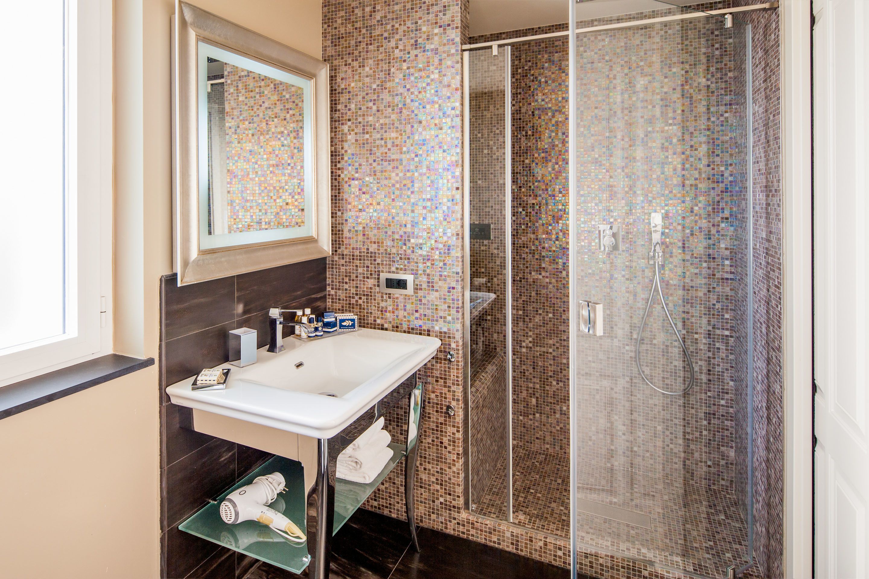 Un baño con ducha de vidrio, un lavabo blanco y un espejo encima.