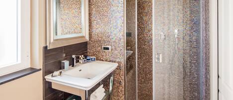 Un baño con ducha de vidrio, un lavabo blanco y un espejo encima.