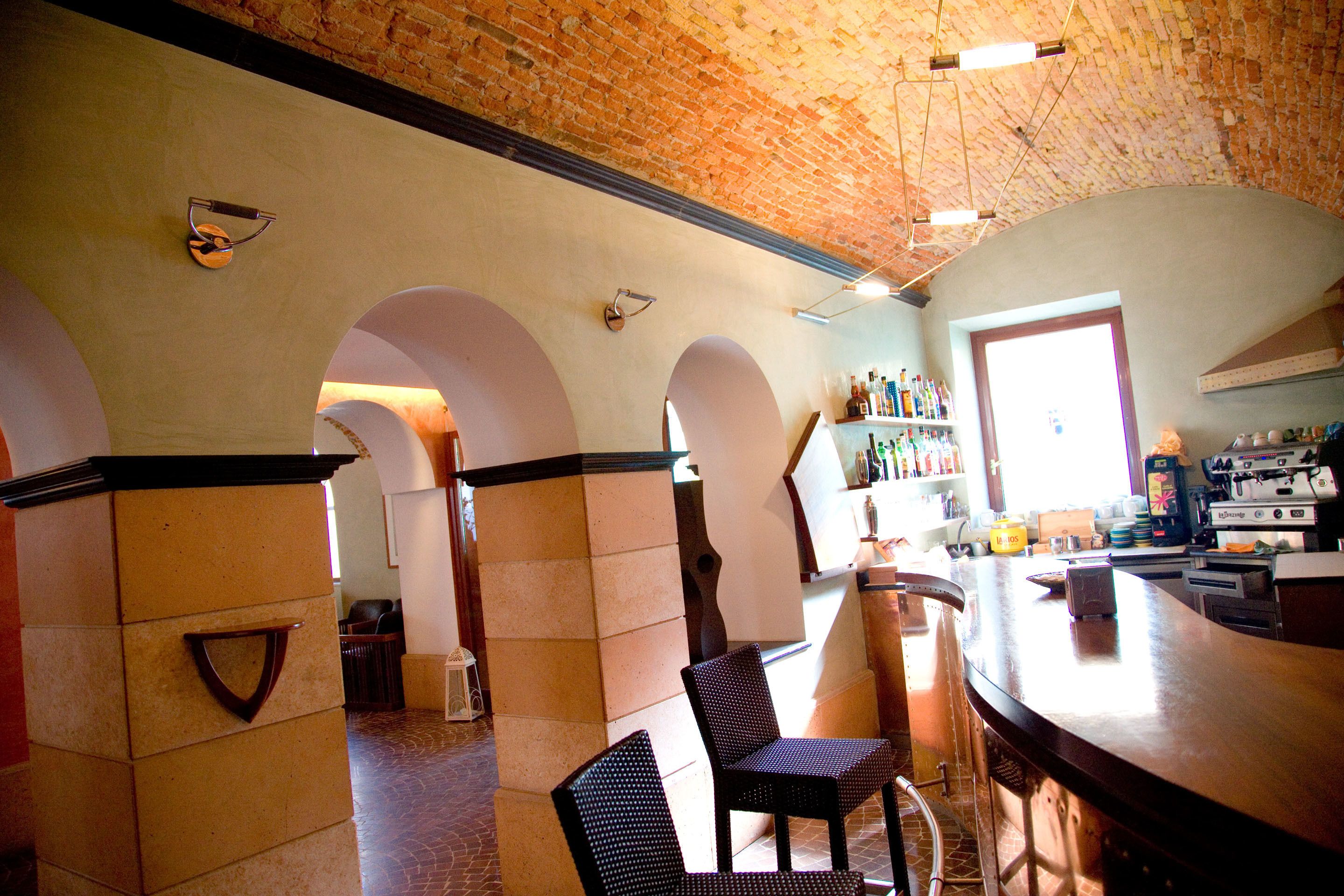 A bar area with a brick ceiling, arched doorways, and a counter with stools.