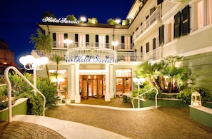 Hotel Savona's entrance with a cobblestone pathway, a covered entrance, and a balcony with railings. - Hotel Savoia (Alassio)