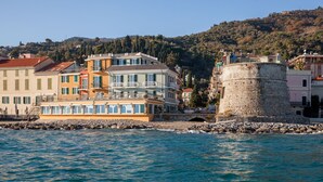 Un pueblo costero con edificios de colores, una torre de piedra y una orilla de mar.