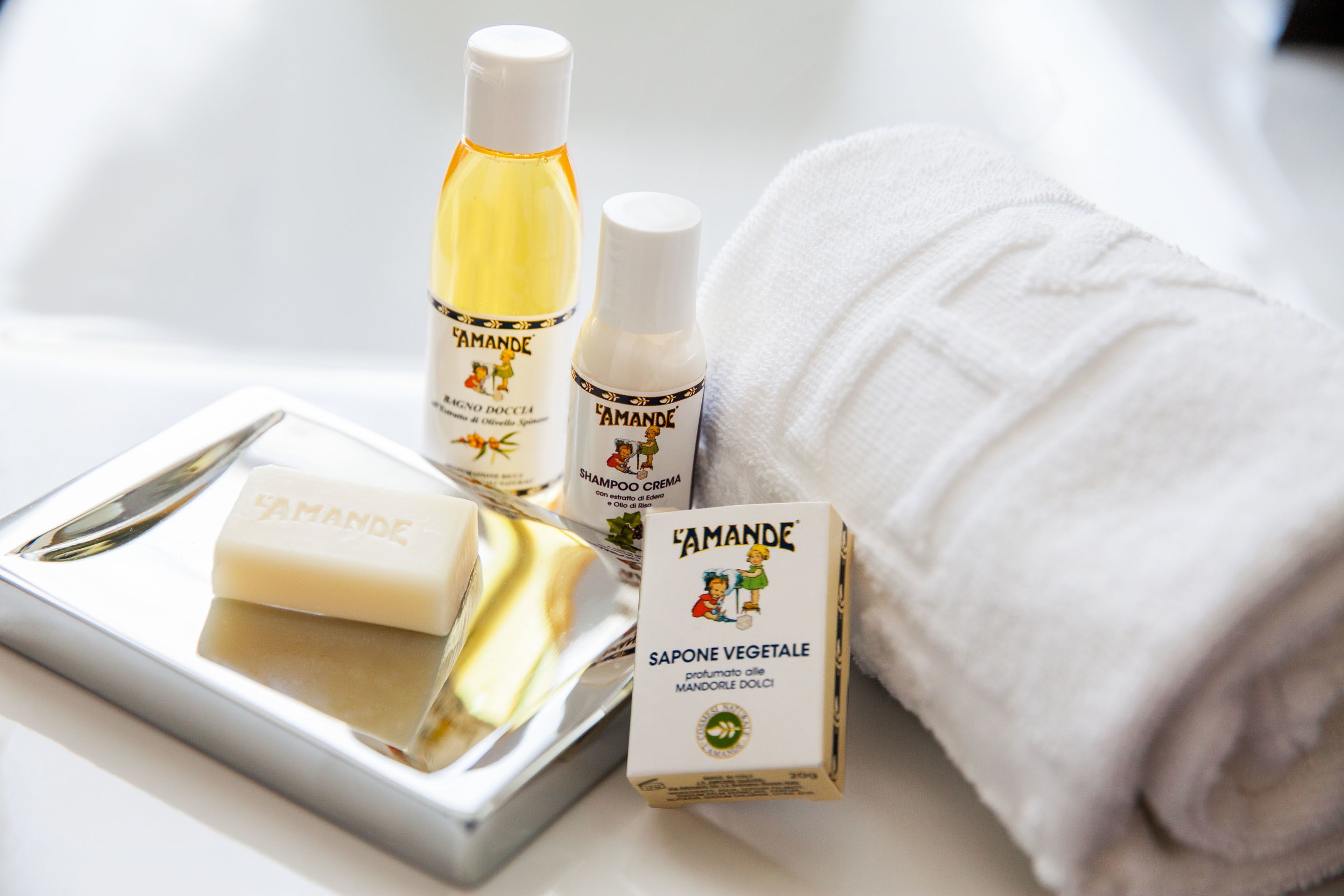 Uma bandeja com sabonete, shampoo, loção e uma toalha enrolada.