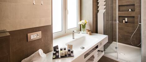 Un baño moderno con tocador blanco, cabina de ducha de vidrio y ventana que proporciona luz natural.