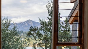 Un dormitorio con un amplio ventanal que ofrece vistas a una montaña y árboles.