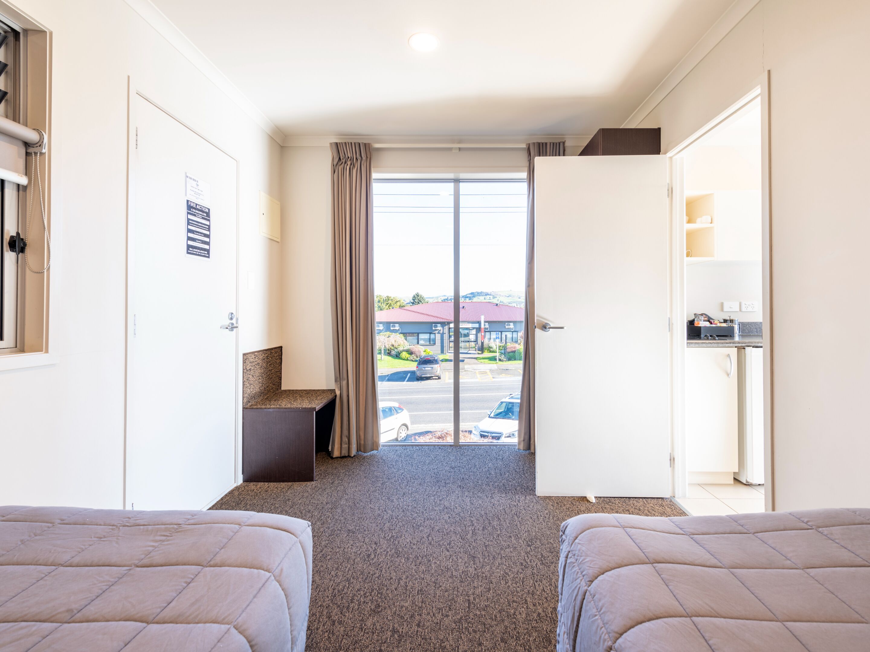 Een hotelkamer met twee bedden, een zithoekje, uitzicht op de straat en een kitchenette.