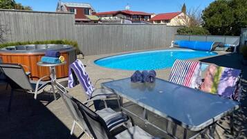 A backyard with a swimming pool, a hot tub, and outdoor seating.