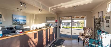 Un espace d’accueil comprenant un comptoir, un ordinateur, une imprimante et une chaise aux motifs colorés.
