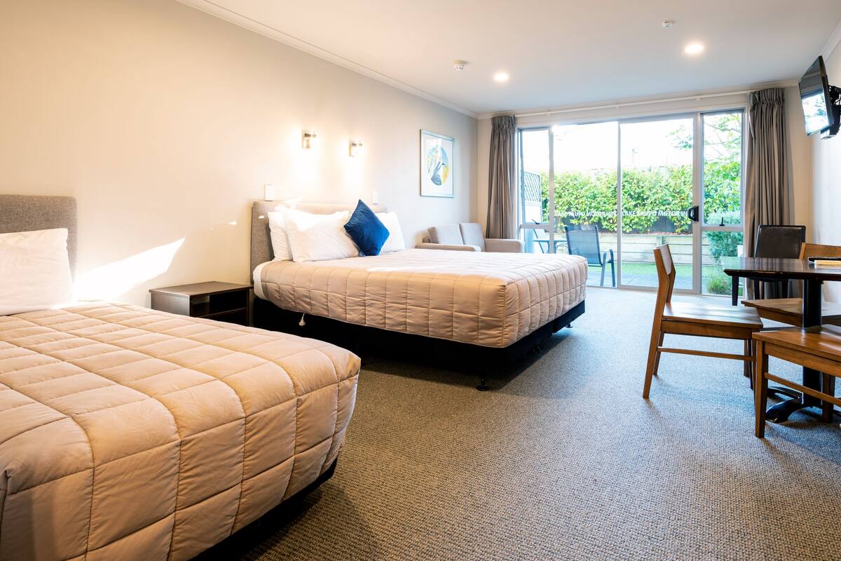 A hotel room with two beds, a desk, and a chair.