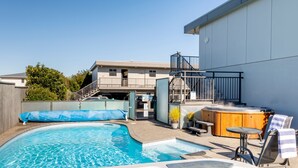 A backyard with a swimming pool, a hot tub, and a covered patio area with outdoor seating. - Lake Taupo Motor Inn (Taupo)
