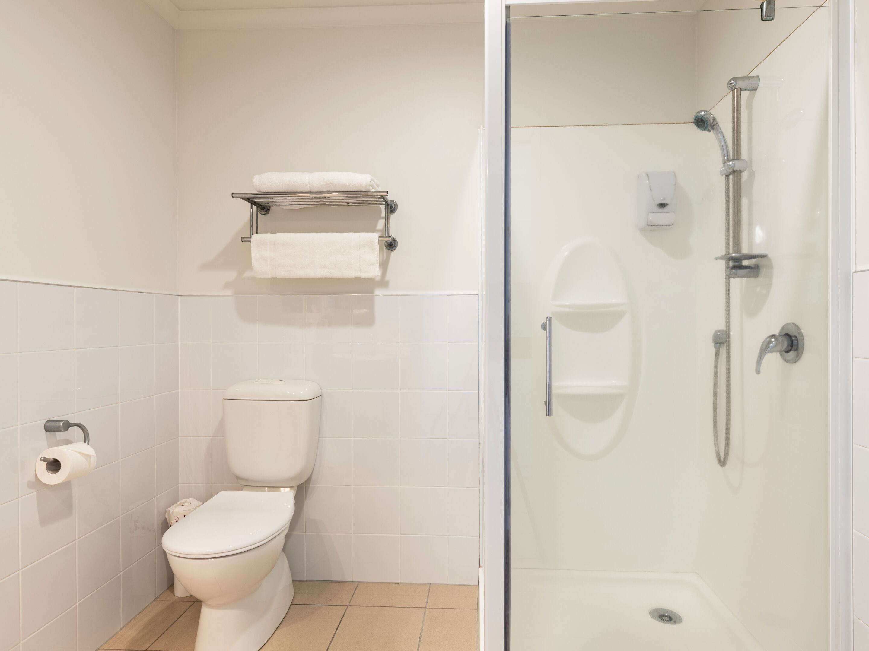 A bathroom with a toilet, a glass-enclosed shower, and a towel rack.