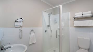 A modern bathroom with a glass-enclosed shower, a sink, a toilet, and a towel rack with folded towels.