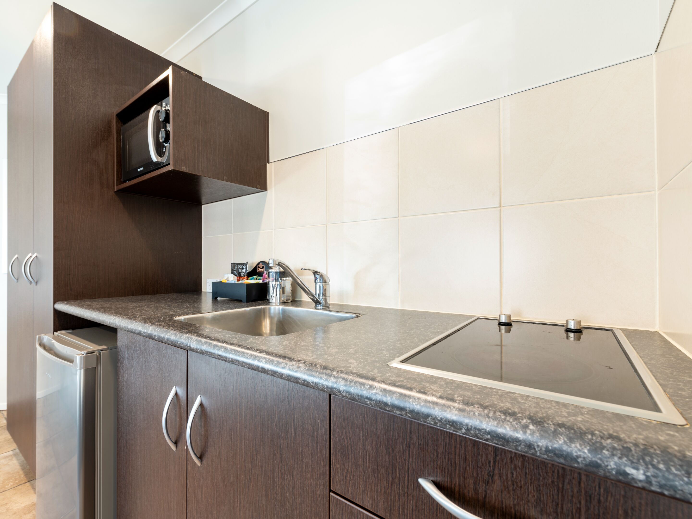 A modern kitchen with a granite countertop, stainless steel sink, and wooden cabinets.
